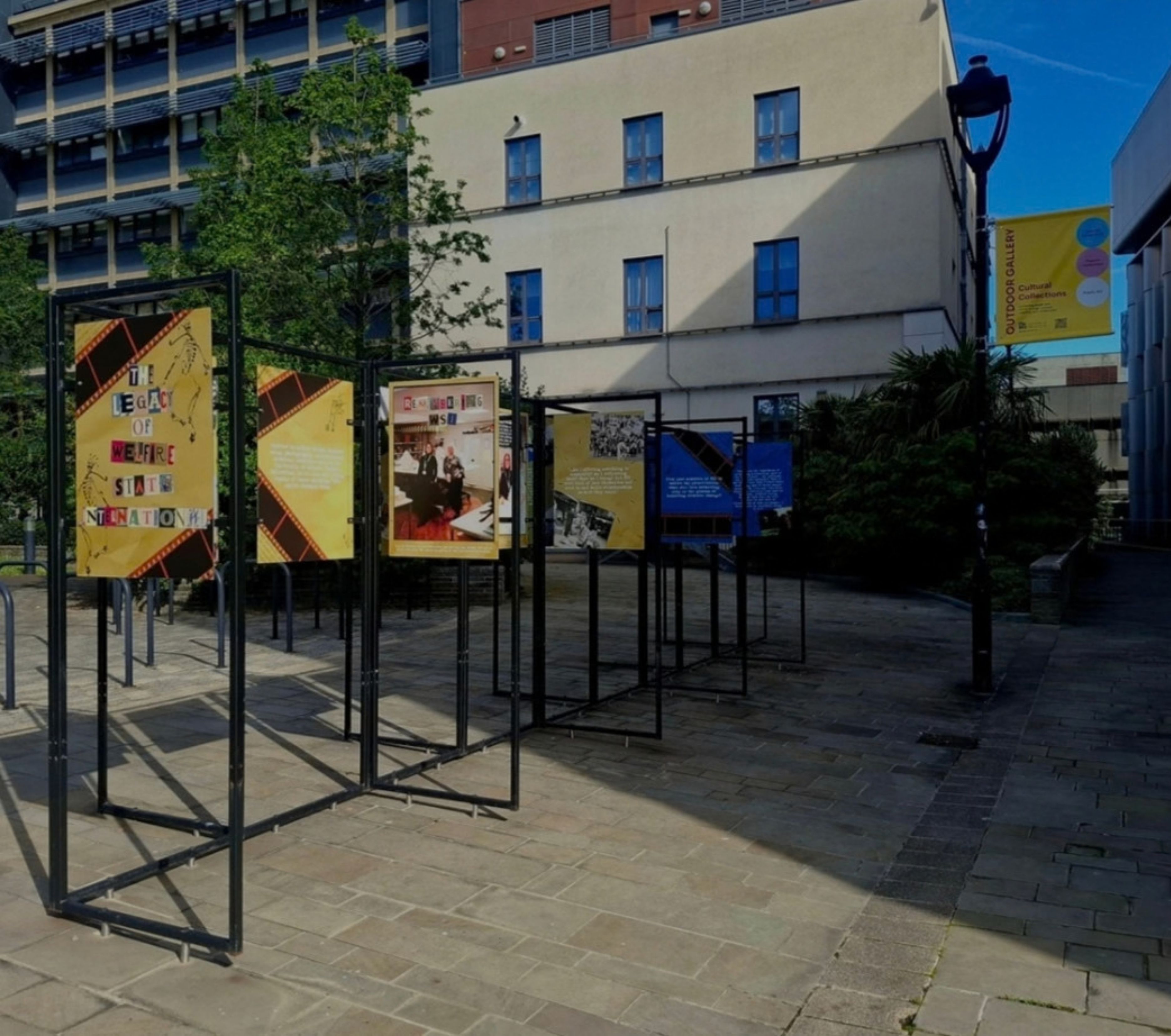 Large display boards in a paved area beside university buildings